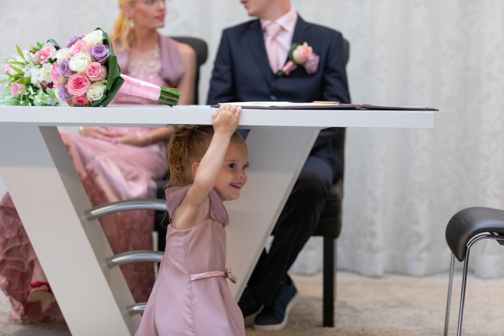 Meisje zit onder de tafel bij het bruispaar tijdens de huwelijksceremonie
